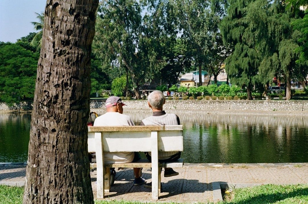 To personer sidder stille på en bænk ved en rolig sø