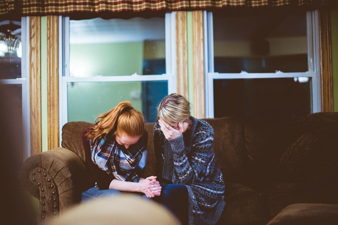 To personer sidder tæt sammen og trøster hinanden i en sofa
